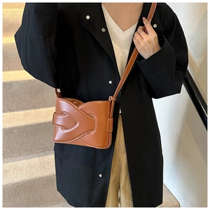 Detail shot of a brown crossbody bag with unique layered woven texture and thin strap