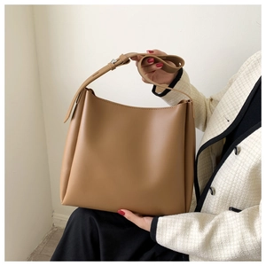 Detail of caramel brown matte leather tote bag with adjustable wide strap and silver eyelets