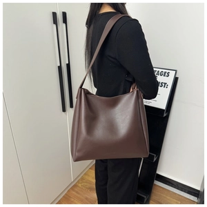 Detailed close-up showing the soft slouchy drape and matte texture of the large brown tote bag
