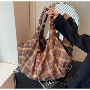 Texture détaillée d'un sac cabas en laine à carreaux marron et violet dans un miroir