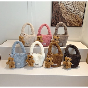 Detail view of plush teddy fleece bucket bags in multiple colors with bear charms