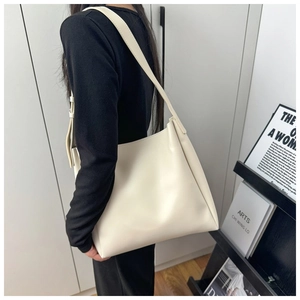 Side view of a cream white minimalist faux leather tote bag worn by a model