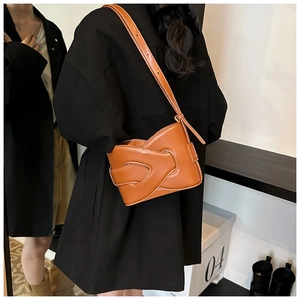 Close-up of brown leather bucket bag with woven pattern and contrast stitching