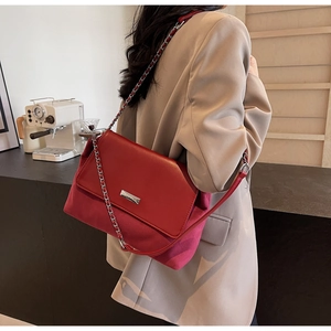 Red flap chain bag in mixed leather finish shown on model with light suit