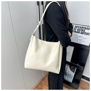 Close-up of a cream white minimalist tote bag with an adjustable strap and smooth texture