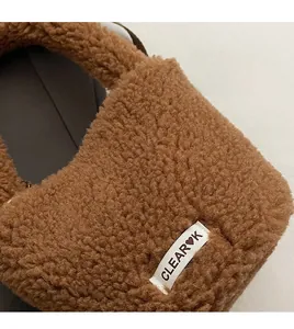 Detailed macro view of soft faux shearling fabric and brand tag on a caramel bucket bag
