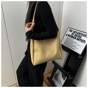Model wearing a cream large capacity tote bag showing shoulder carry strap and soft leather