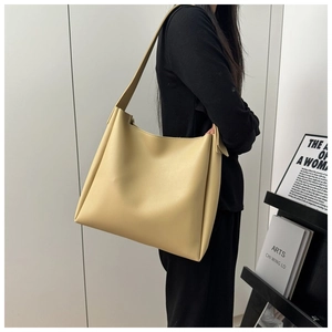 Minimalist beige tote bag shown on shoulder model, highlighting large capacity and drape