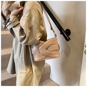 Detail of minimalist beige leather bucket bag with elegant overlapping fold design