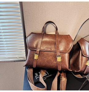 Detailed view of a vintage brown leather satchel with double buckles and woven strap