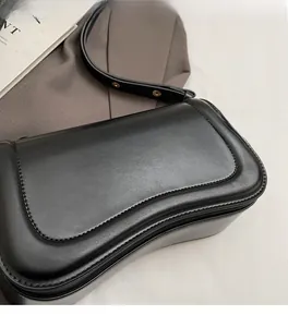 Détail d'un sac à rabat en cuir noir avec design ondulé et surpiqûres fines