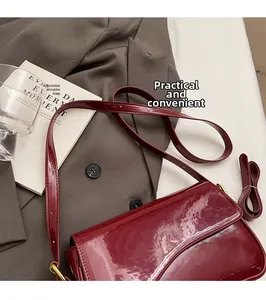 Detail of burgundy patent leather bag with adjustable strap on a stylish blazer