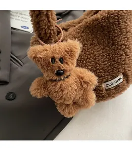 Close-up of a brown plush bear charm and textile brand label on a soft bucket bag