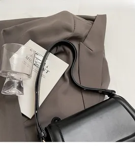 Sac à rabat minimaliste en cuir noir sur blazer avec détail de bandoulière réglable