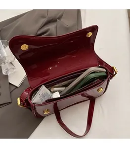 Detail view of burgundy patent leather bag interior with magnetic buckles and large storage space