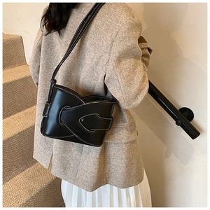 Detail of black crossbody bag featuring contrast white stitching on matte leather texture