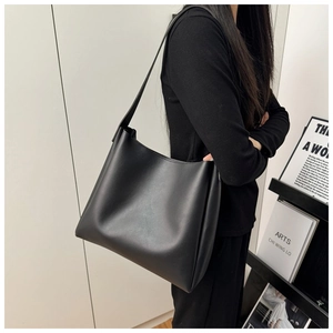 Minimalist black faux leather tote bag shown from a side view for daily commuting