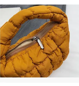 Détail du sac nuage matelassé jaune montrant la fermeture éclair et la texture du tissu