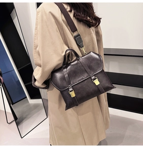 Detail view of vintage dark brown satchel bag featuring white contrast stitching and gold buckles