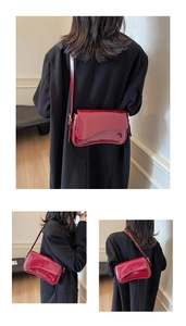 Detail showing red patent leather shoulder bag with wavy flap and adjustable metal buckle