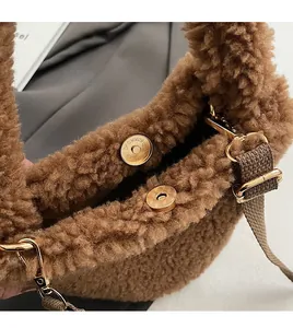 Detail of golden magnetic clasp on brown faux fur plush bucket bag with soft texture