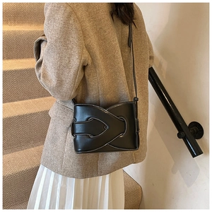 Chic black leather bucket bag with contrast stitching and unique woven knot detail on model