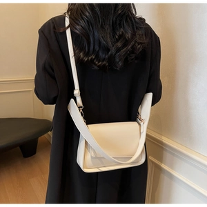 Detail view of the cream beige crossbody bag on a model wearing a black suit