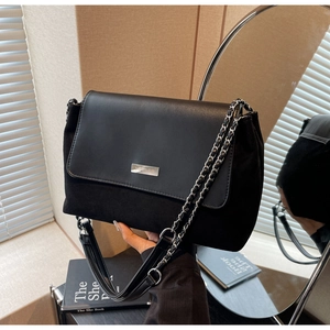 Detail of black leather shoulder bag with gold chain strap and brand logo plaque