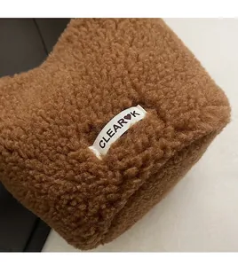 Detailed close-up of brown faux shearling bucket bag with a white CLEAR♥K woven label