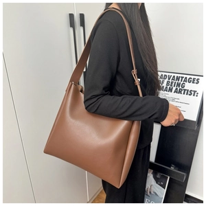 Side view of a brown vintage tote bag worn by a model in a minimalist setting