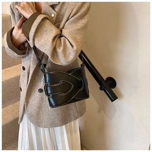 Detail of premium black leather bucket bag with contrasting white stitching and layered flap