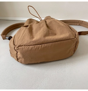 Detail view of the caramel nylon backpack showing bottom base and padded shoulder straps