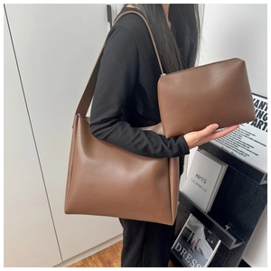 Detail view of large brown leather tote bag with matching zipper pouch on a model