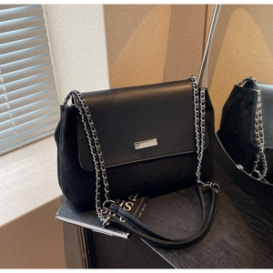 Detail view of black patchwork shoulder bag with silver chain and brand metal plaque