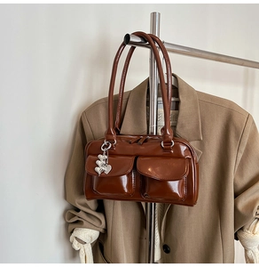 Detail of a vintage dark brown tote bag featuring silver heart charm and dual side pockets