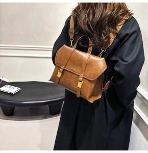 Brown vintage PU leather backpack with gold metal buckles and woven shoulder straps on model