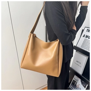 Close-up of a khaki large-capacity leather tote bag with a wide strap on a model