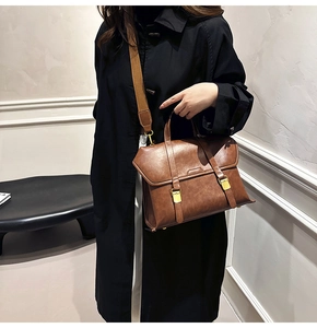 Detail view of retro brown leather handbag with gold buckles and wide shoulder strap