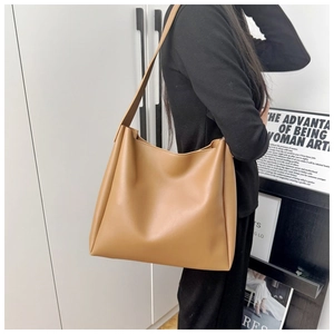 Detail view of the spacious light brown leather tote bag with wide shoulder strap on a model