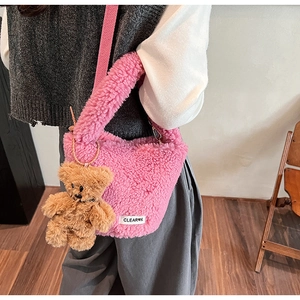 Close-up of pink faux shearling bucket bag with teddy bear charm and logo patch