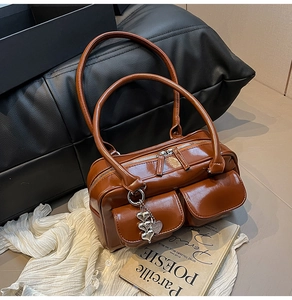 Close-up of brown faux leather handbag featuring dual front pockets and heart charms