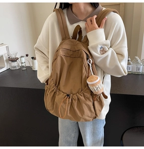 Brown nylon backpack detail featuring side drawstring pocket and cute coffee cup pendant