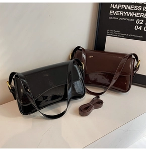 Detail of minimalist patent leather shoulder bags in black and dark brown with gold hardware