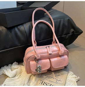 Detailed shot of pink patent leather handbag with silver heart charm and zip closure