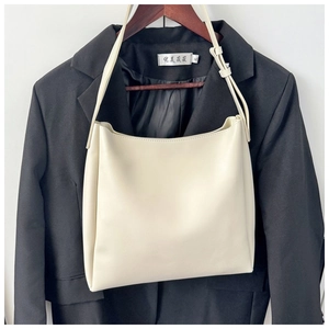 Close-up of adjustable shoulder strap with gold buckle on cream-white PU leather bucket bag