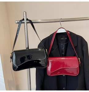 Detail showing glossy patent leather shoulder bags in black and dark red with asymmetric flap