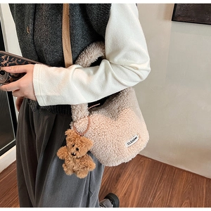 Close-up of fluffy beige faux fur bucket bag with a cute brown teddy bear pendant detail