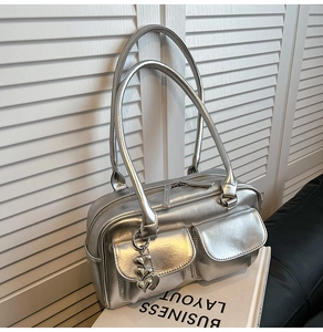 Close-up of metallic silver tote bag with heart chain detail and dual front flap pockets