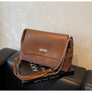 Detailed view of the brown leather and suede patchwork shoulder bag on a book