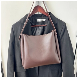 Detail view of smooth dark coffee leather texture and strap stitching on tote bag